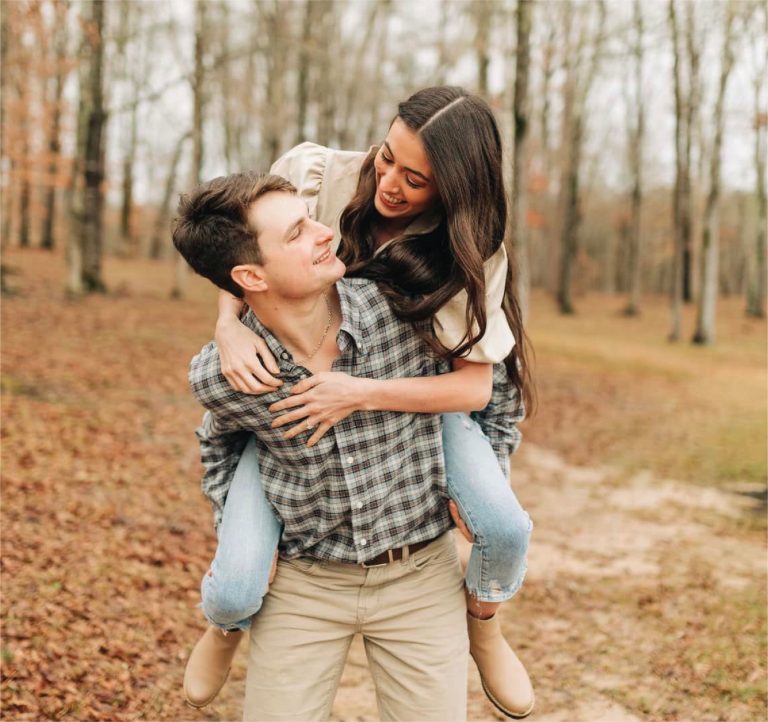 Engaged couple laughing and holding hands at Brookwood Venue in Oxford, Mississippi, with scenic lake backdrop.
