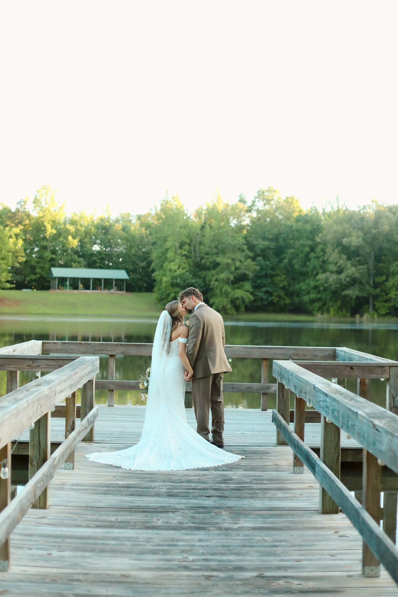 Couple holding hands on lakeside dock at Brookwood Venue, Oxford, Mississippi.