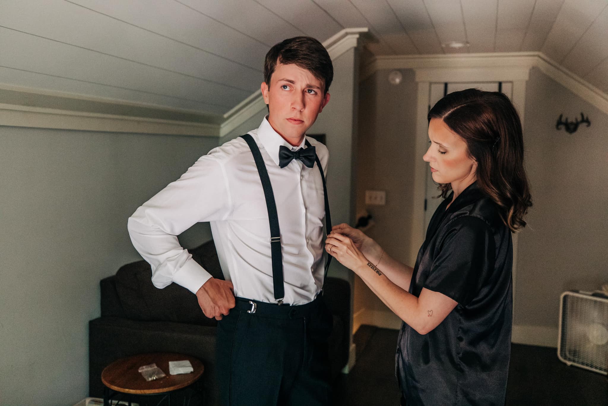 Groom straightening jacket before ceremony in rustic cabin at Brookwood Venue, North Mississippi