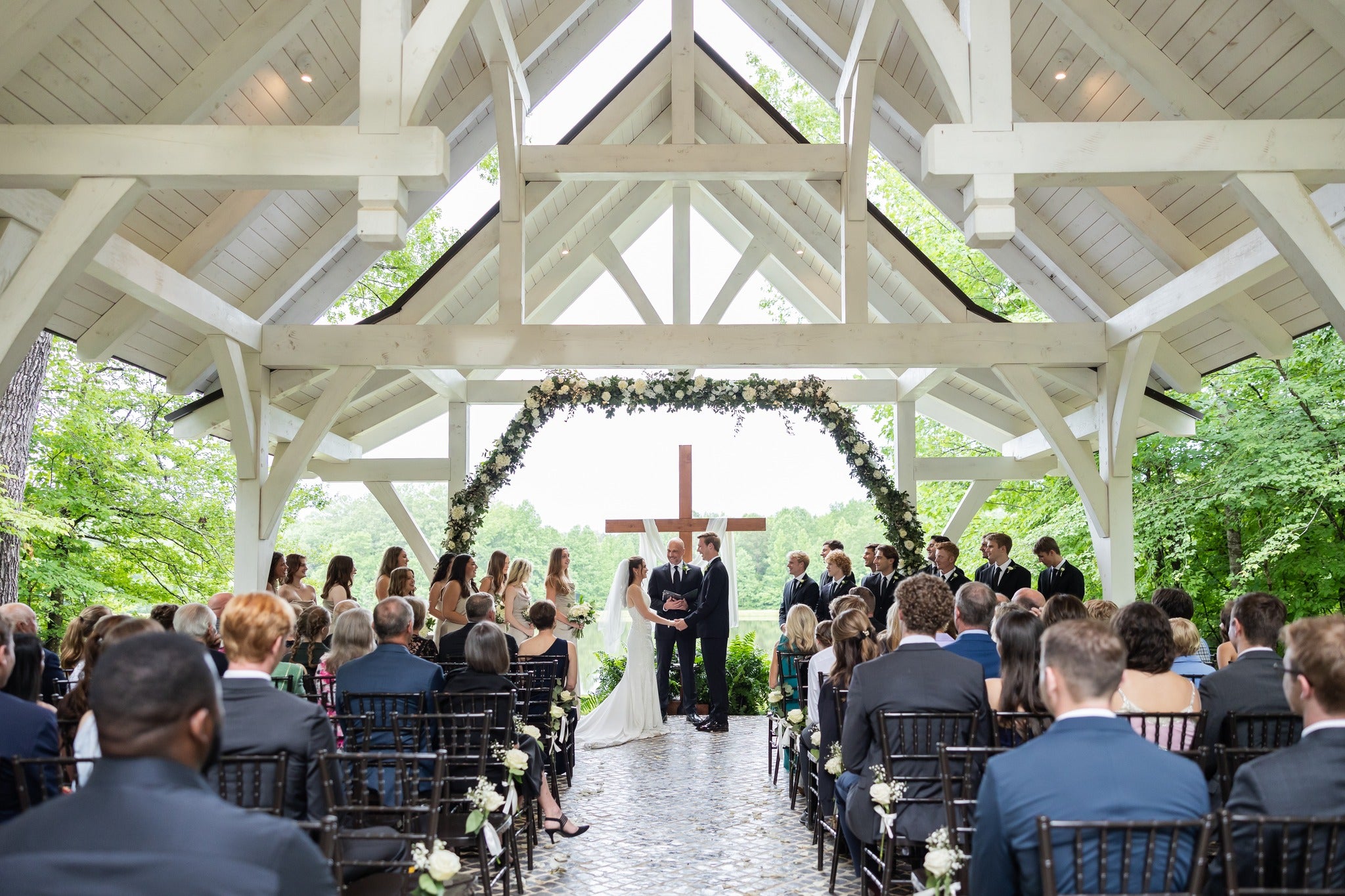 Charming lakeside chapel at Brookwood Venue with rustic white exterior, wooden pews, and floral wedding decorations – perfect for intimate ceremonies in Oxford,Mississippi.