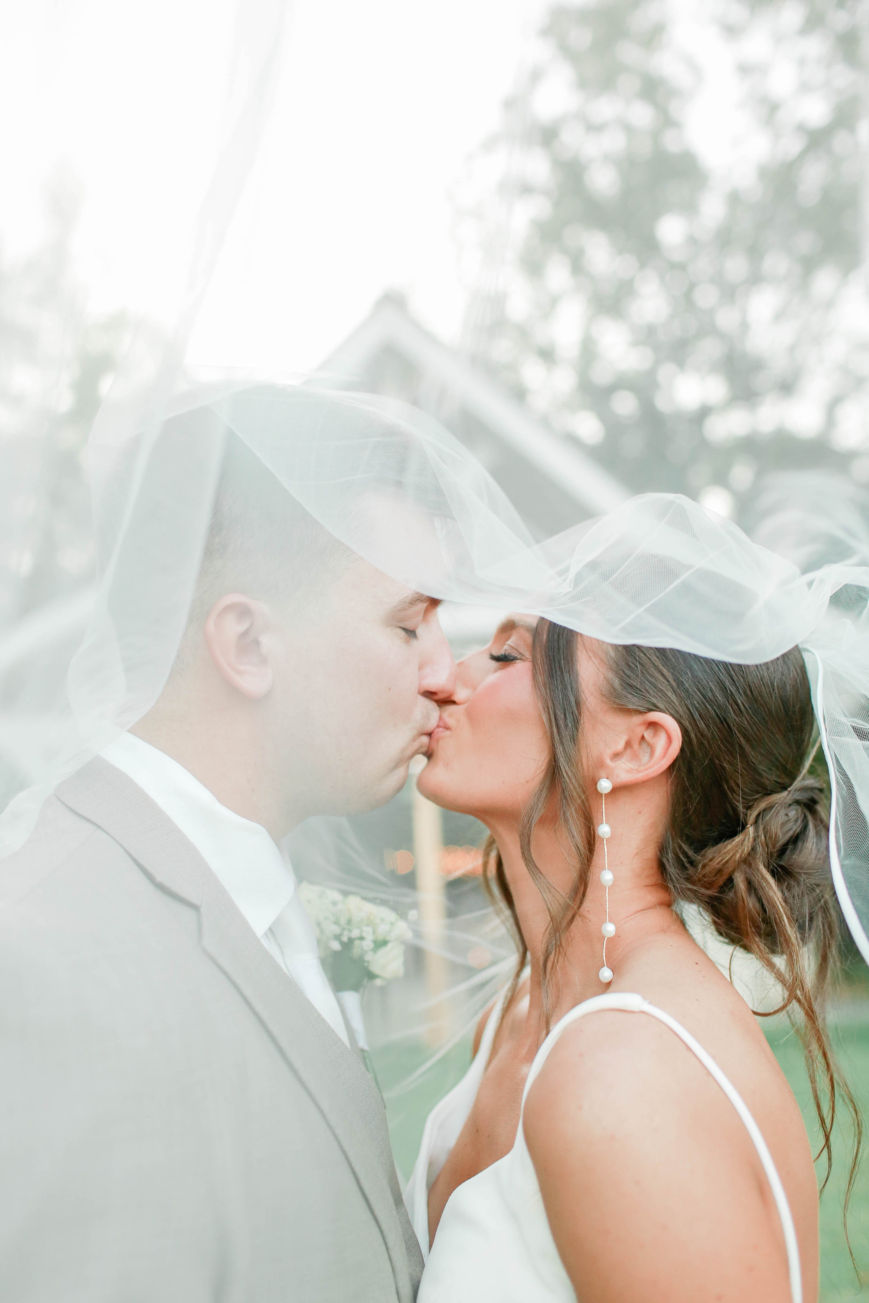 Bride and groom kissing by lake at Brookwood Venue near Oxford, Mississippi.