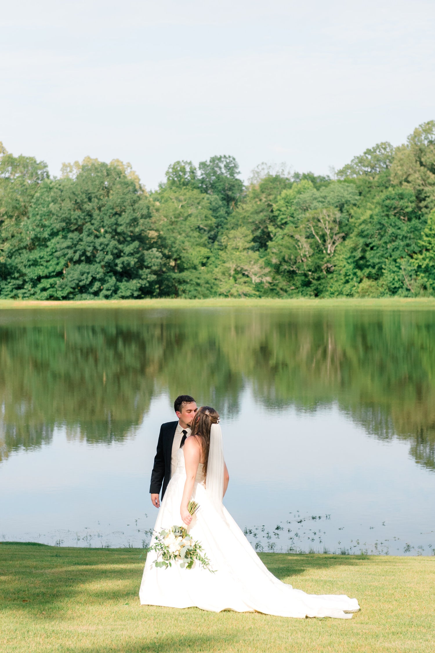 bride and groom kissing during wedding photos at affordable Mississippi lakeside venue 
