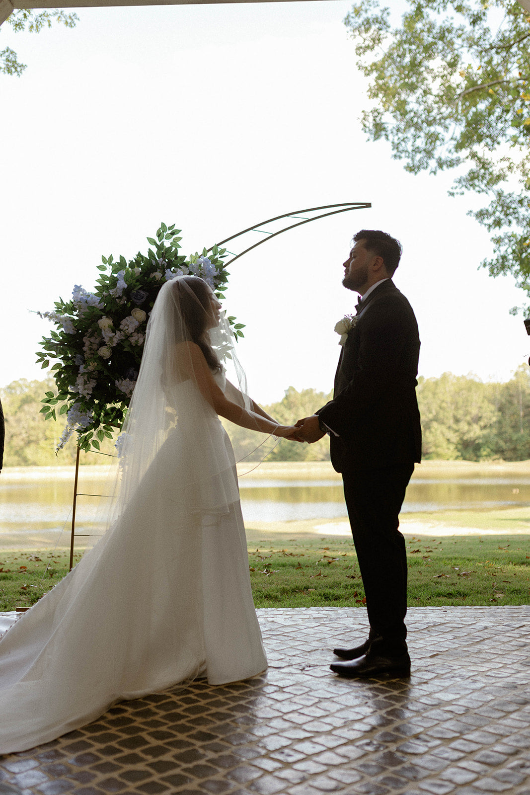 bride and groom holding hands saying wedding vows lakeside in bruce,mississippi