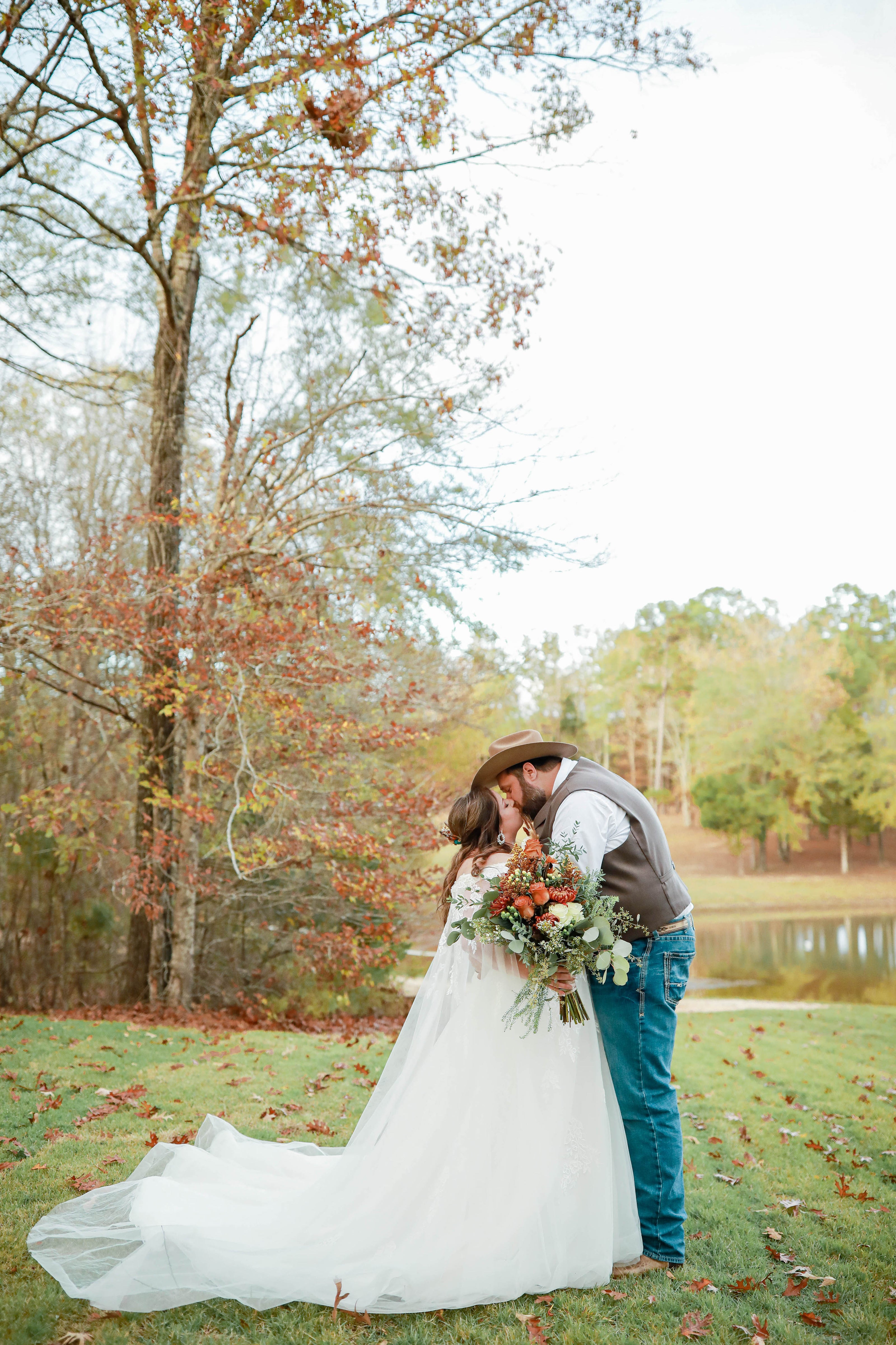 Bride and groom kissing by lake at Brookwood Venue near Oxford, Mississippi.