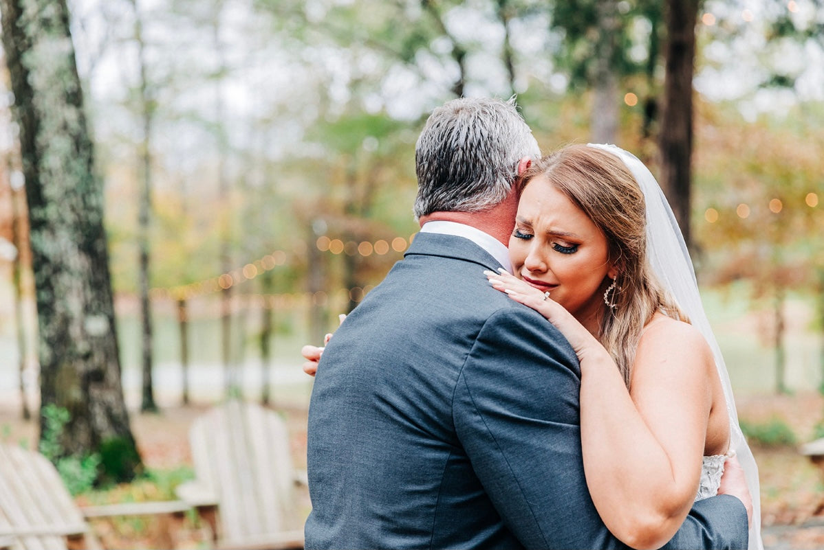 bride hugging father before ceremony in cabin at Brookwood Venue near Oxford, Mississippi.