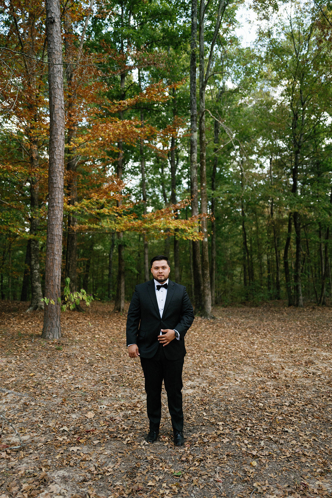 groom in tux posing for wedding portrait in woods near oxford mississippi