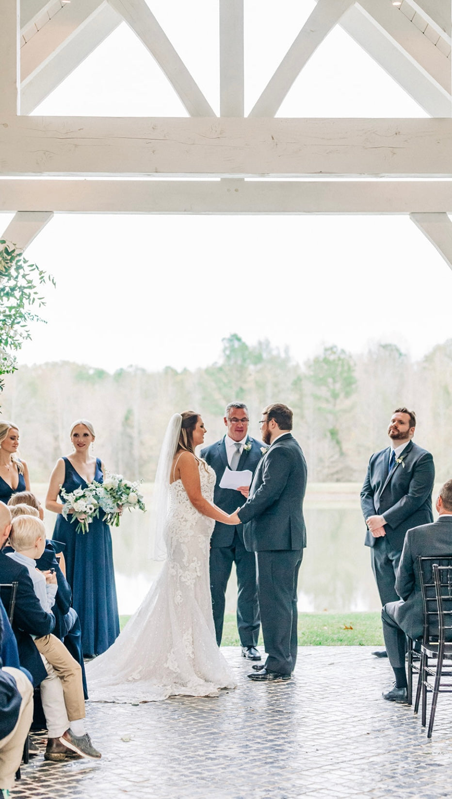 Bride and groom holding hands at altar in Brookwood Venue lakeside chapel.