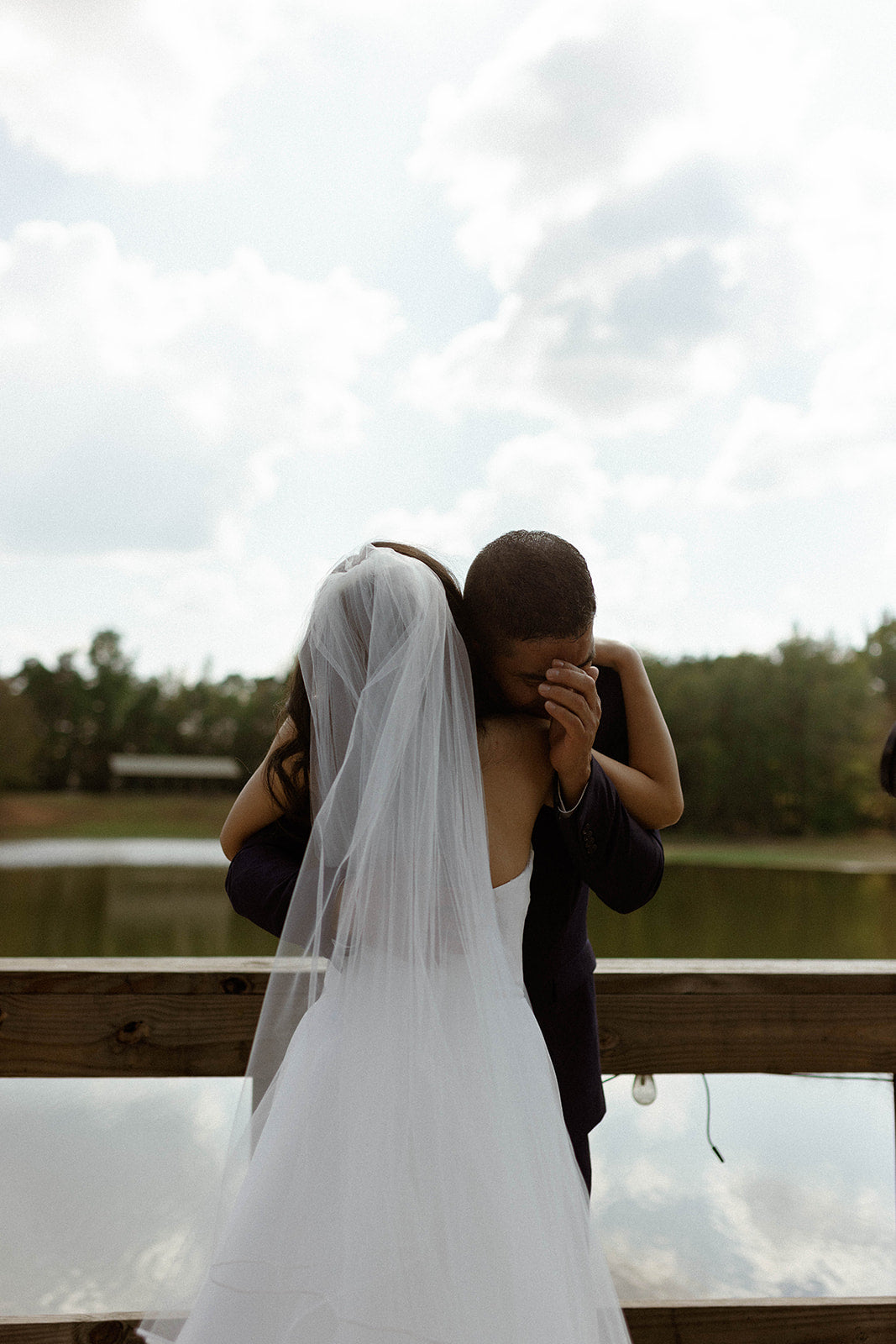 father crying during wedding photos with bride at lakeside wedding venue in mississippi