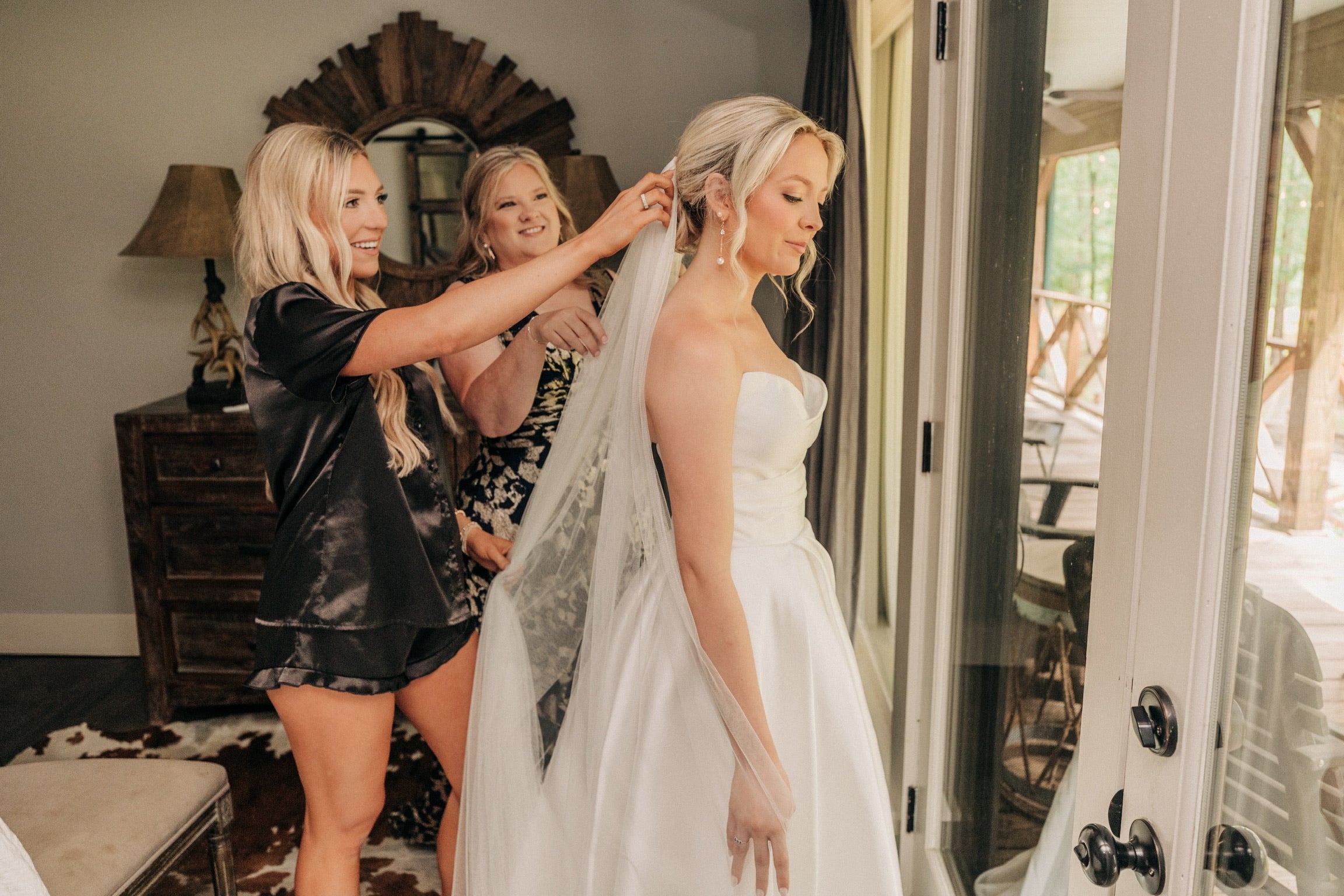 Mother helping bride with veil in North Mississippi wedding cabin.
