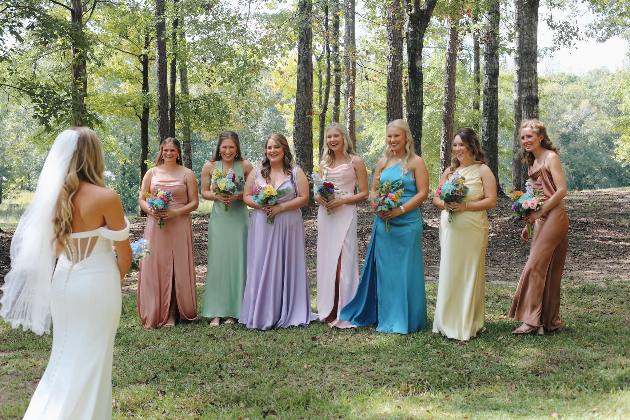 Bride surrounded by bridesmaids in scenic outdoor setting at Brookwood Venue.