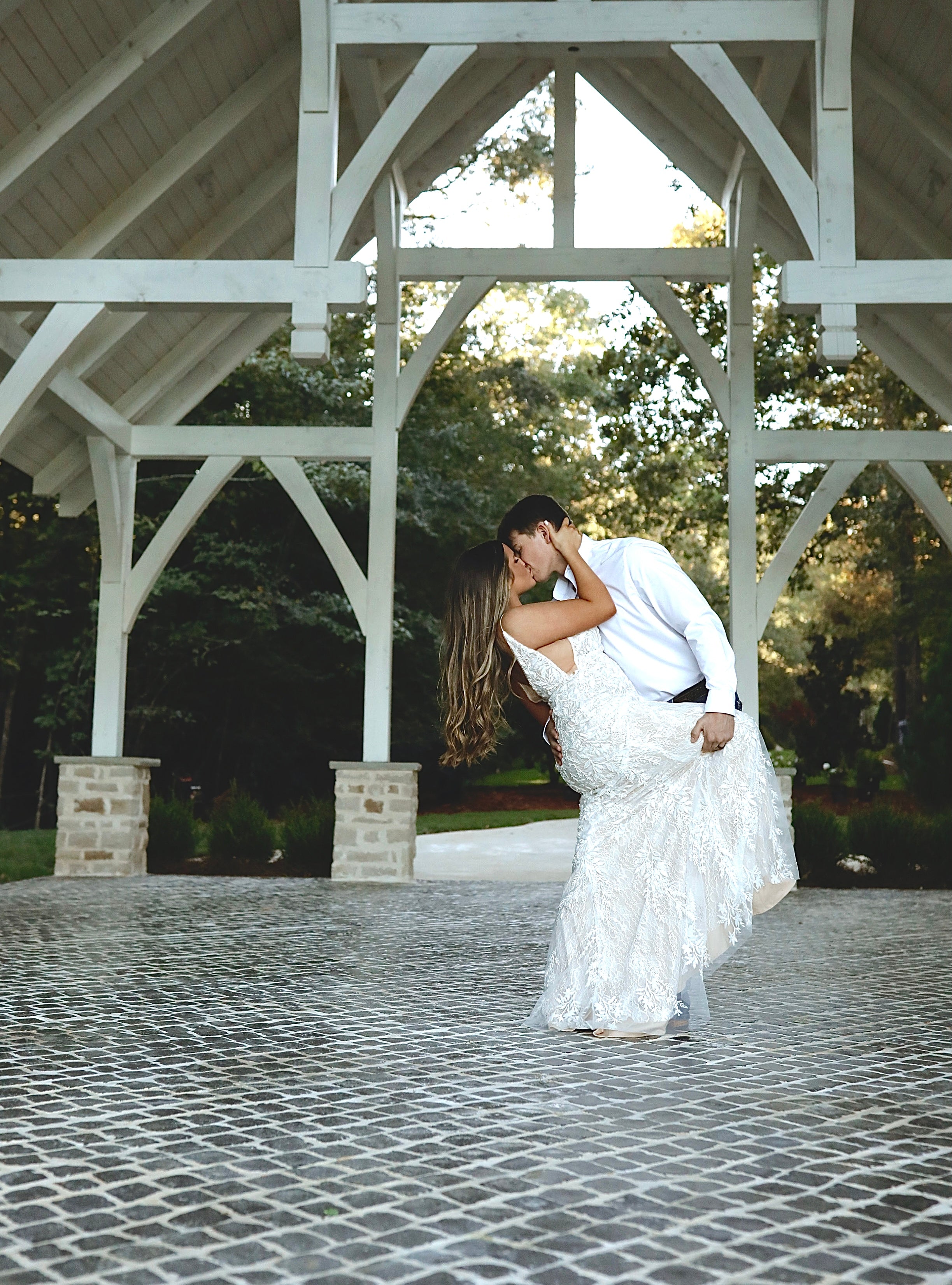 bride and groom kissing during wedding portraits under white chapel near tupelo