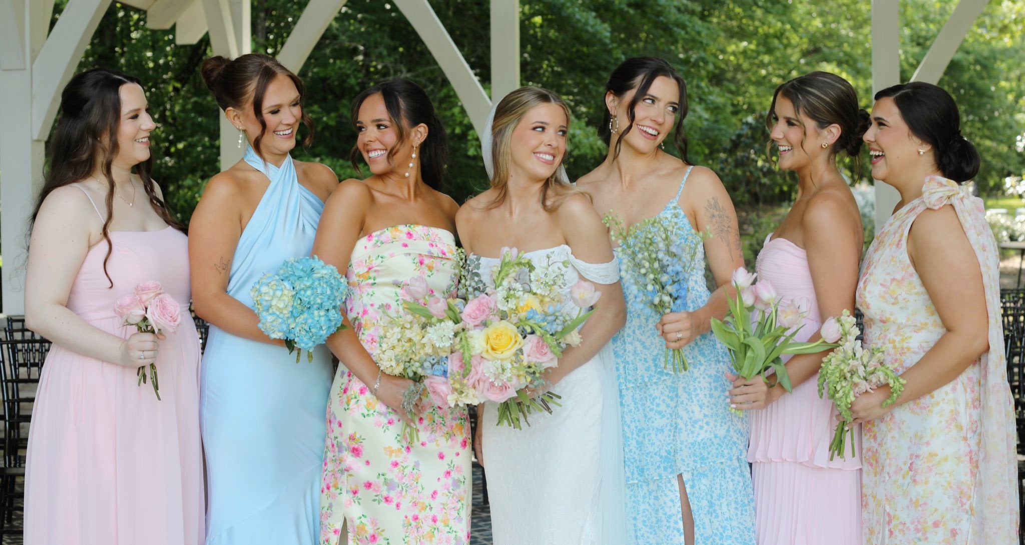 Bride surrounded by bridesmaids in scenic outdoor setting at Brookwood Venue.